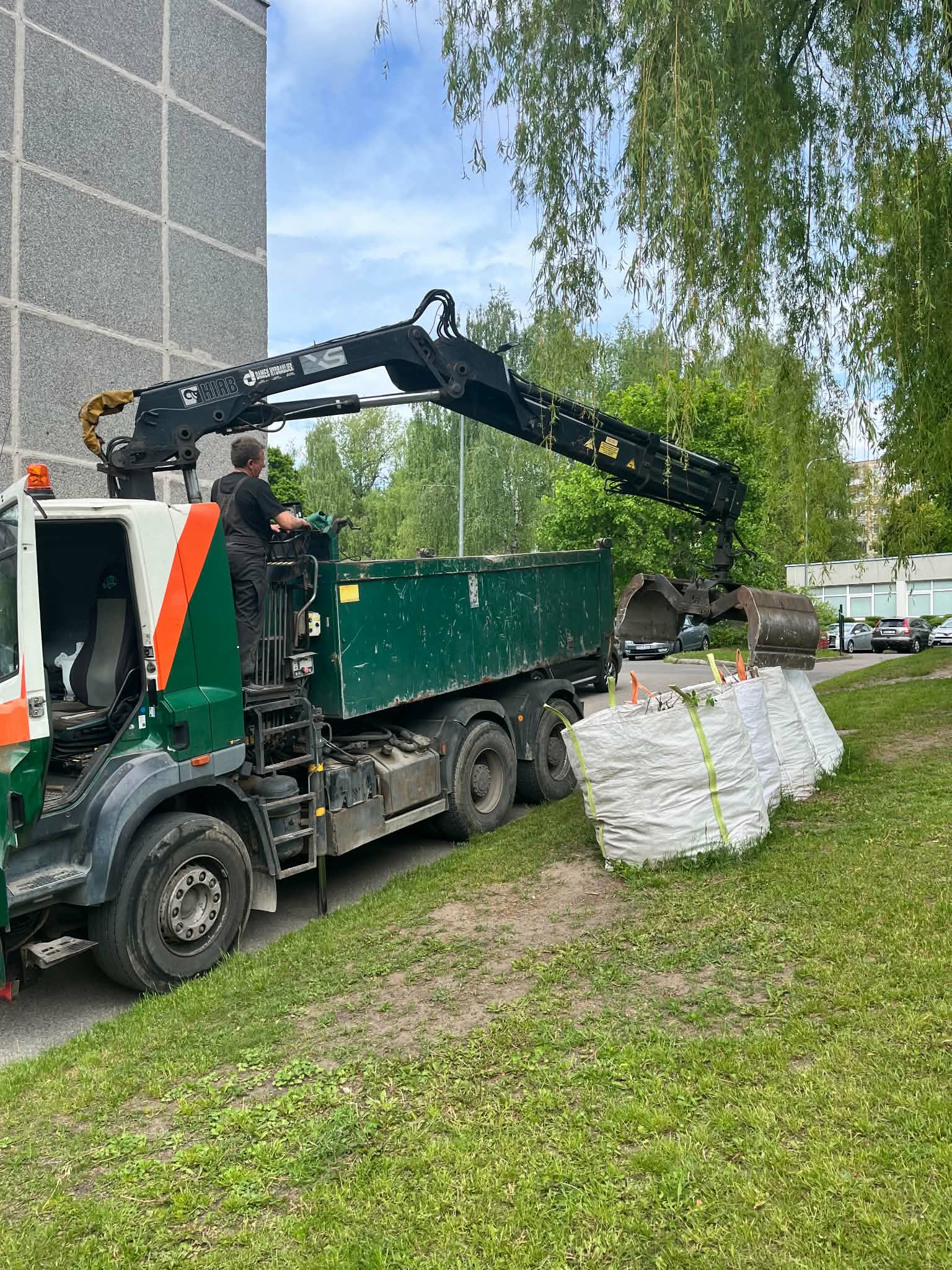 Savivartis su griebtuvu prie pakrautų statybinių atliekų maišų